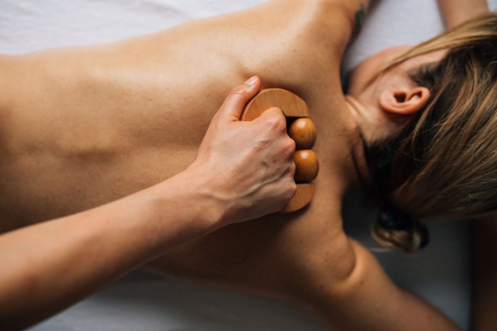 Mujer recibiendo maderoterapia corporal con elementos de madera en una cabina de estética
