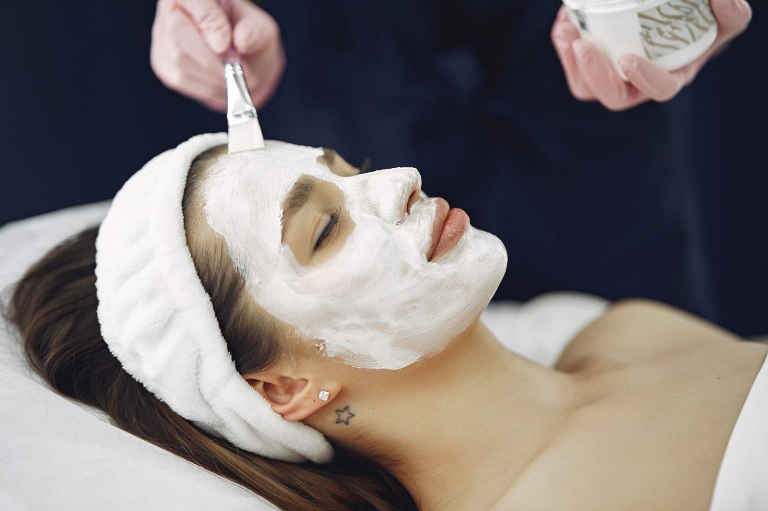 Esteticista aplicando cosmética facial durante el tratamiento Soin Tomate Glow en cabina